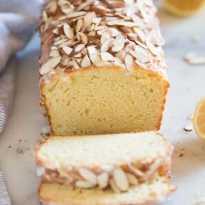 A loaf of lemon almond bread with two slices cut from it.