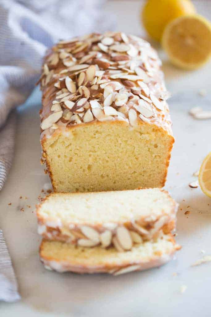A loaf of lemon almond bread with two slices cut from it.