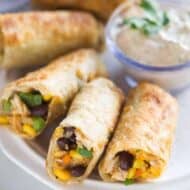 Southwest egg rolls on a plate with creamy cilantro dipping sauce.