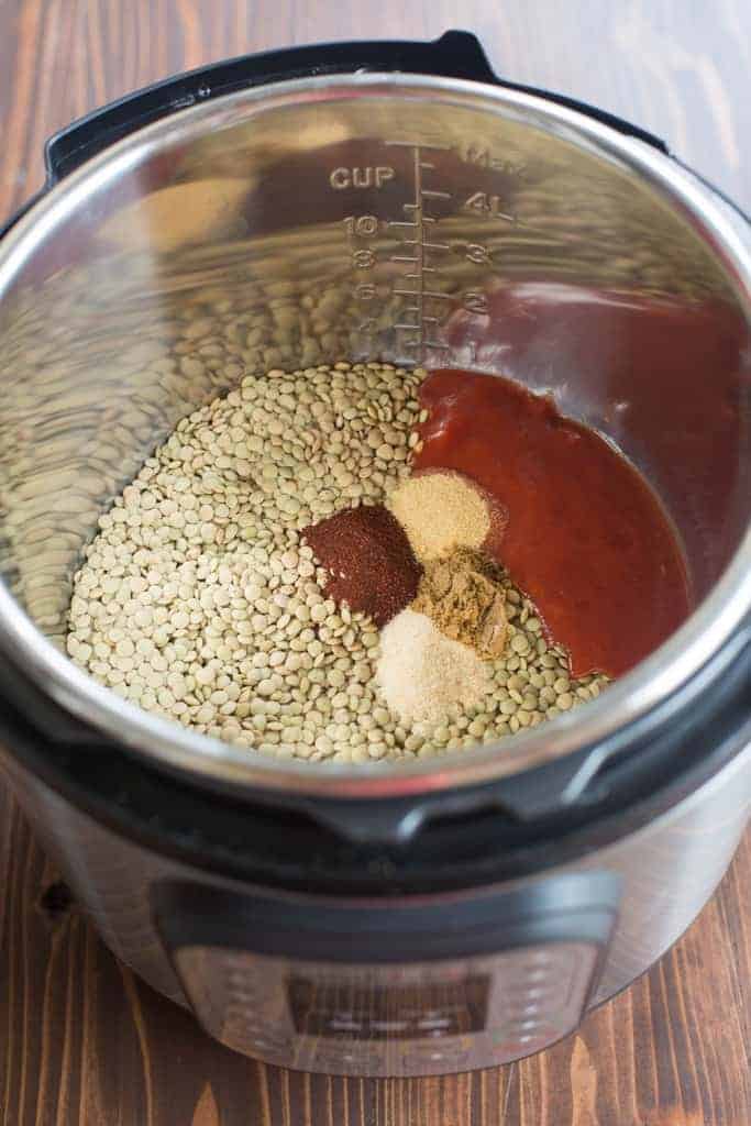 An instant pot filled with the ingredients needed for lentil tacos including lentils, salsa, and spices.