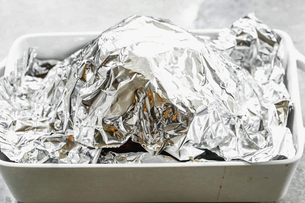 A spiraled ham in a baking dish, covered with foil.