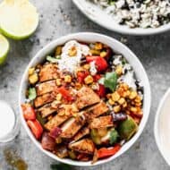 A fajita bowl with rice and black beans topped with grilled vegetables and chicken.