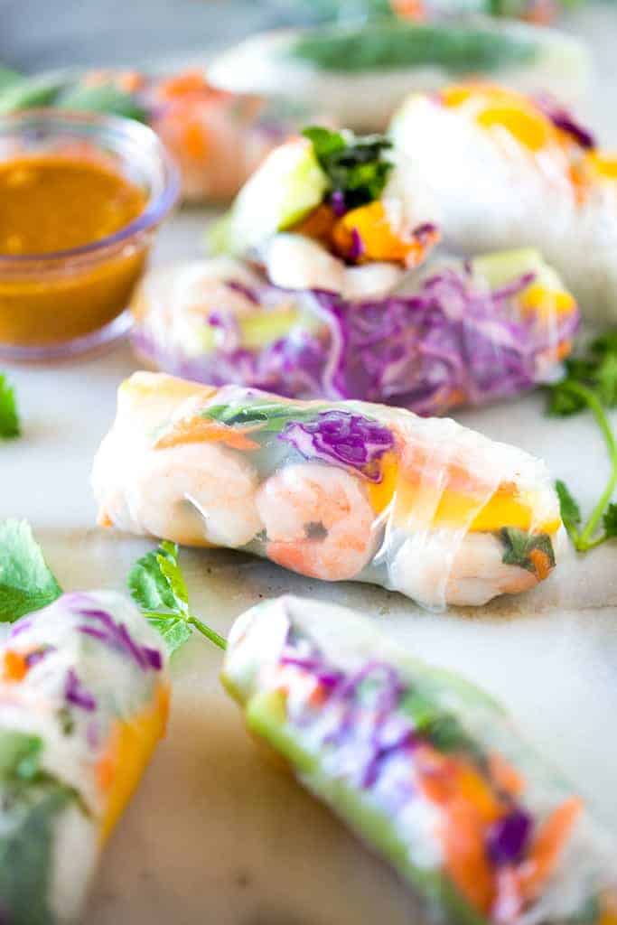 Fresh spring rolls on a white board with a side of peanut sauce.
