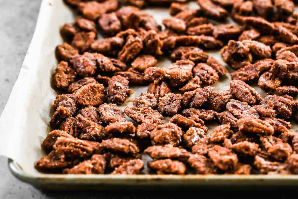 A baking sheet with candied pecans on parchment paper.