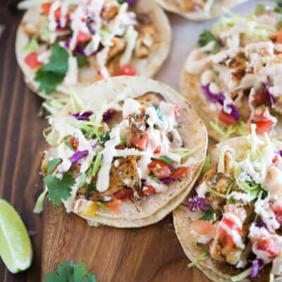 Fish tacos served on white corn tortillas and piled with toppings including cabbage, cilantro, pico de gallo and a white sauce