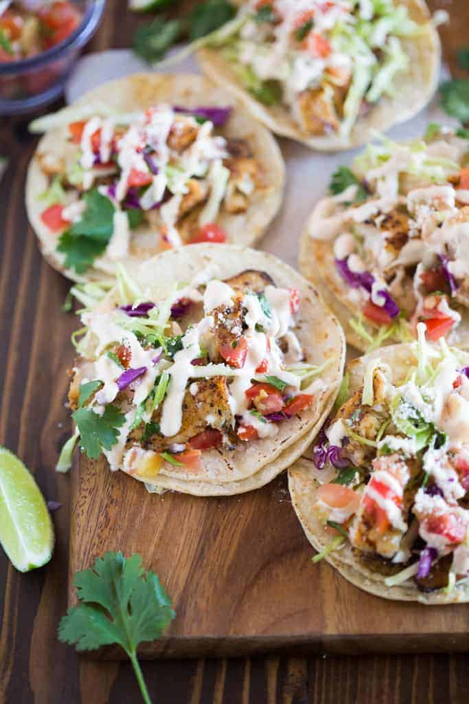 Fish tacos served on white corn tortillas and piled with toppings including cabbage, cilantro, pico de gallo and a white sauce