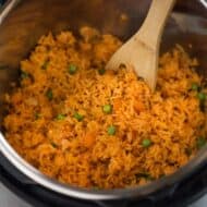 Cooked Mexican rice inside an instant pot, served with a wooden spoon.