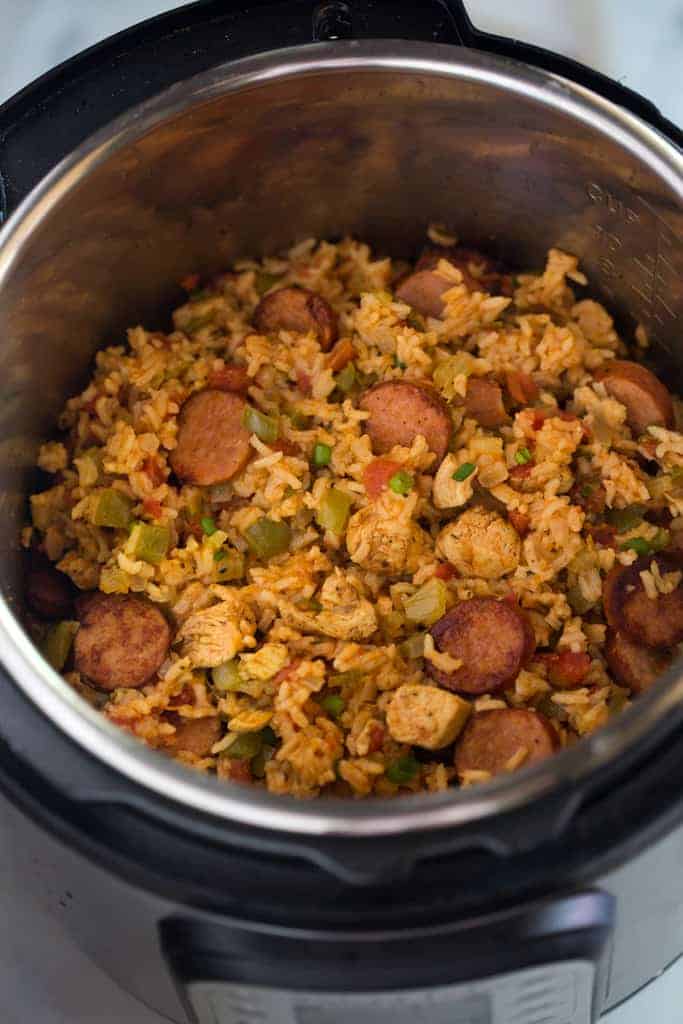 An instant pot filled with cooked jambalaya, ready to serve, including rice, chicken and sausages.
