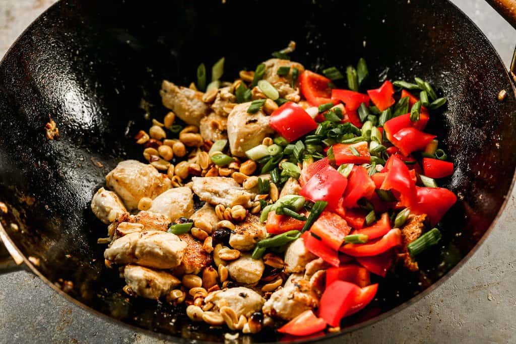 Chicken, veggies and peanuts sautéing in a wok.