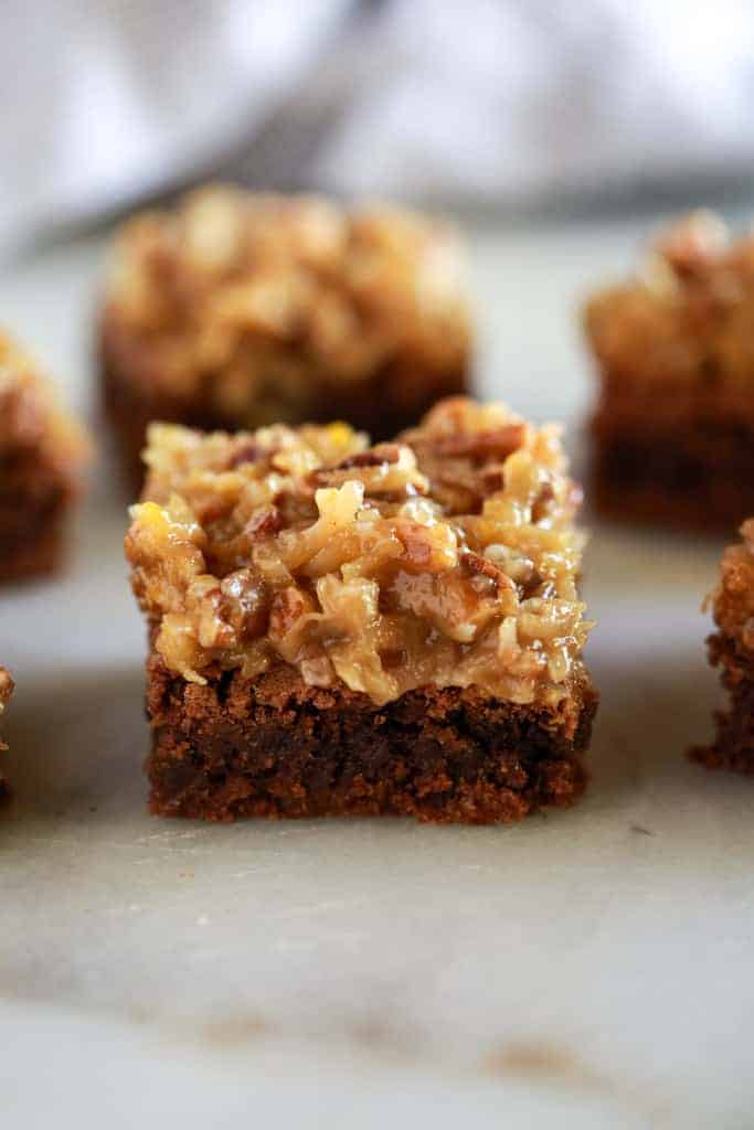 Cut German chocolate brownies served on a white board. 
