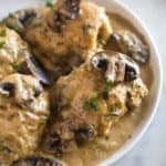 Chicken marsala that was made in the instant pot with chicken thighs and marsala wine, served on a white plate with sauce and mushrooms.