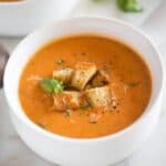 Instant Pot Tomato Basil Soup with parmesan served in a white bowl with a handle and topped with homemade croutons.