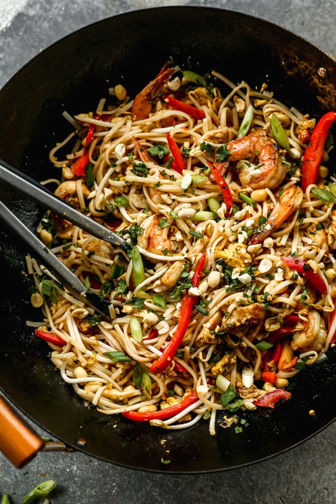 Easy Homemade Pad Thai cooked in a wok, with tongs for serving.