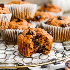 Healthy pumpkin muffins on a cooling rack, with a bite taken from one.