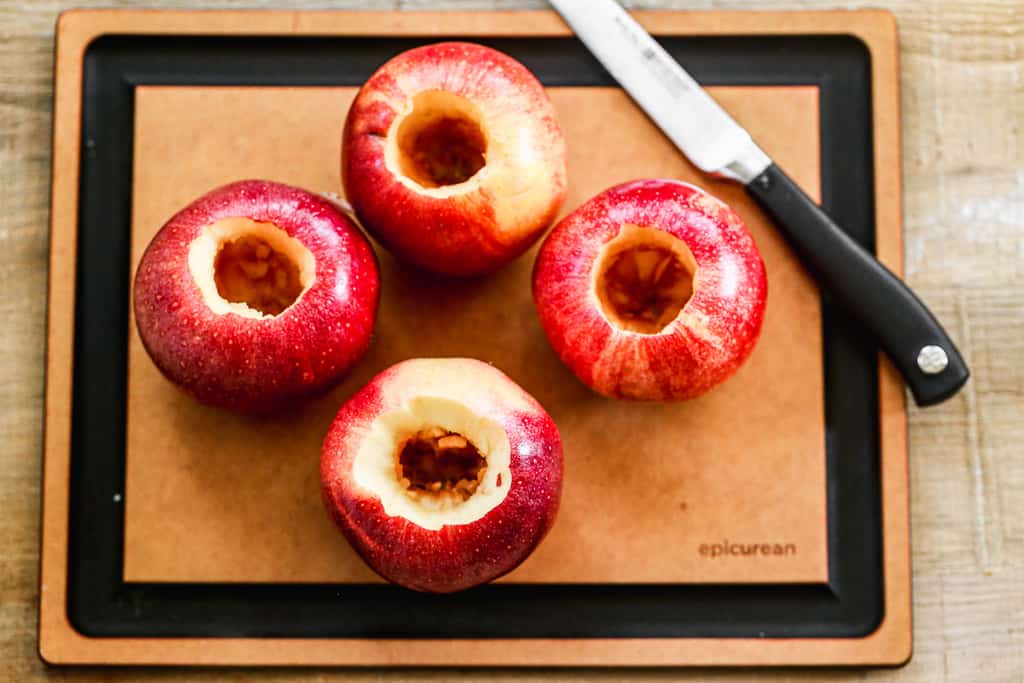 Quatre grosses pommes sur une planche à découper, avec les noyaux retirés.
