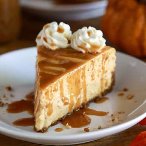 A slice of pumpkin cheesecake on a white plate with caramel sauce drizzled on top.