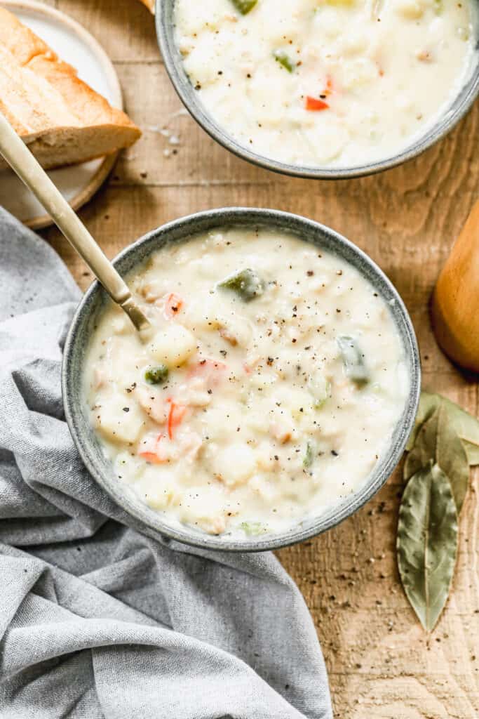 A bowl of homemade clam chowder, with a spoon in it.