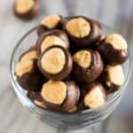 A small glass bowl filled with buckeye peanut butter balls which are a no bake candy made with peanut butter, powdered sugar and dipped in chocolate.