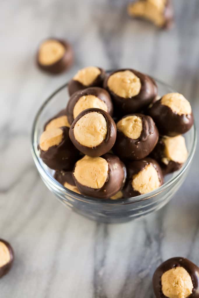 A small glass bowl filled with buckeye peanut butter balls which are a no bake candy made with peanut butter, powdered sugar and dipped in chocolate.