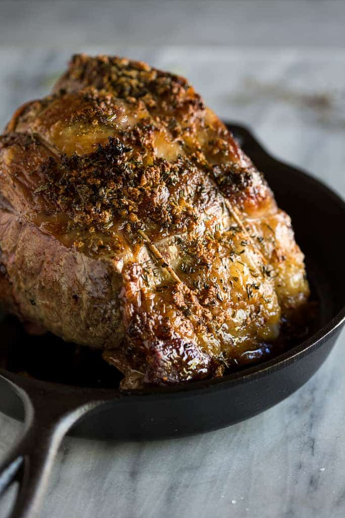 A fully cooked standing rib roast (prime rib) in a cast iron skillet.