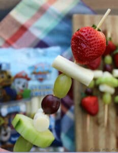 A kabobs with grapes, cucumber slices, mozzarella cheese and whole strawberries.