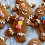 Gingerbread cookies decorated as gingerbread men with white frosting and colored gumdrops.