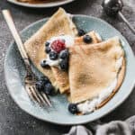 Three French crepes with whipped cream and berries on top, ready to enjoy.