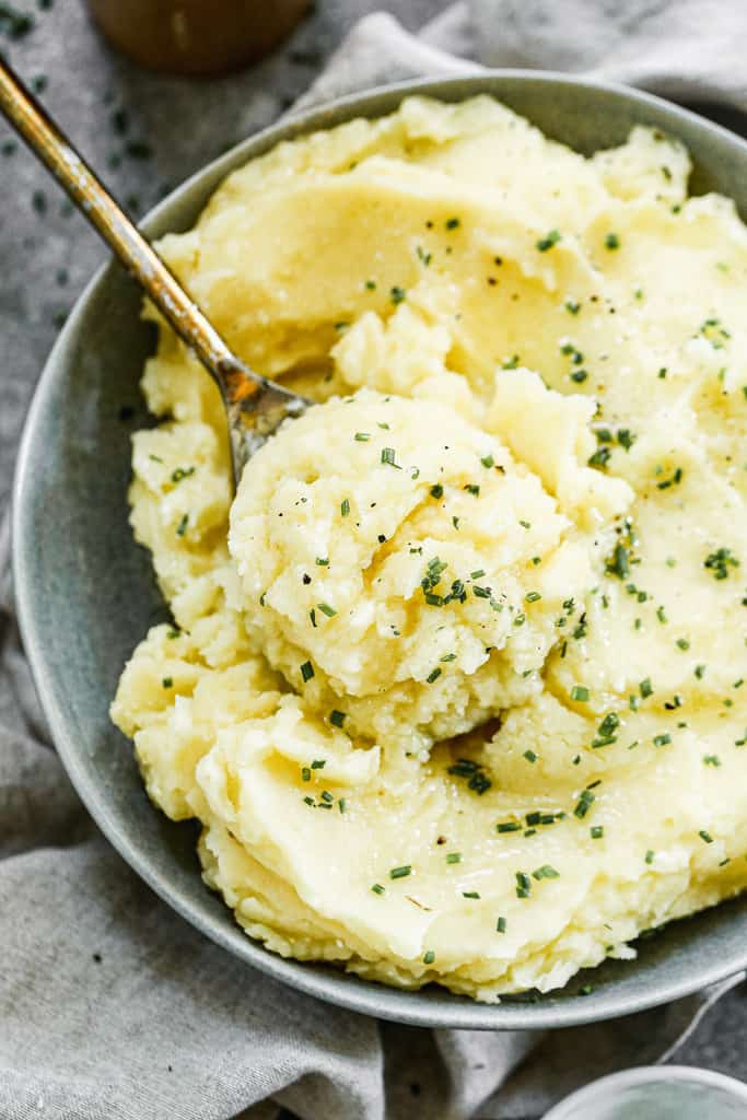 Instant Pot Mashed Potatoes served in a bowl, with a serving spoon.