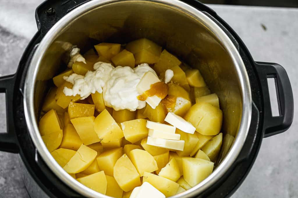 Cooked potatoes in an instant pot, with sour cream, butter and milk added on top.