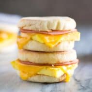 Two egg, ham and cheese breakfast sandwiches made on English muffins, stacked on top of each other.