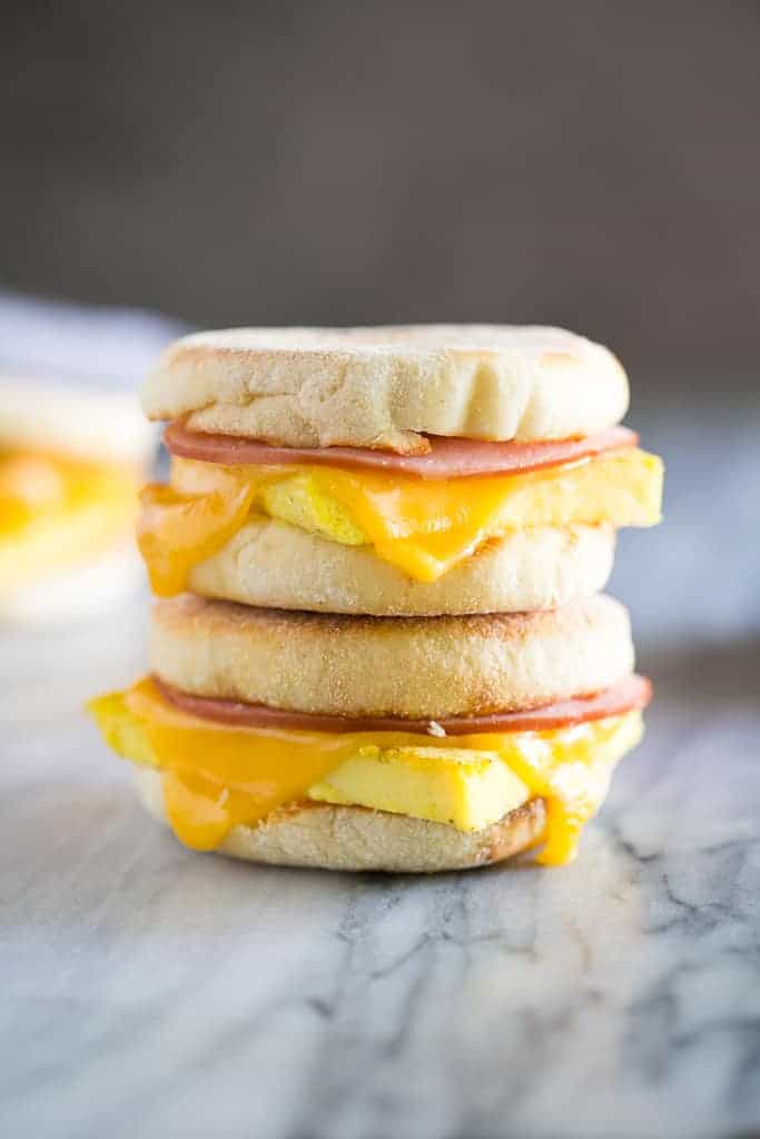 Two egg, ham and cheese breakfast sandwiches made on English muffins, stacked on top of each other.