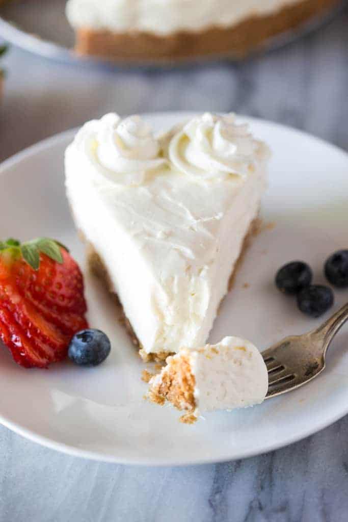 No-Bake-Cheesecake slice on a plate with a fork taken a bite out.