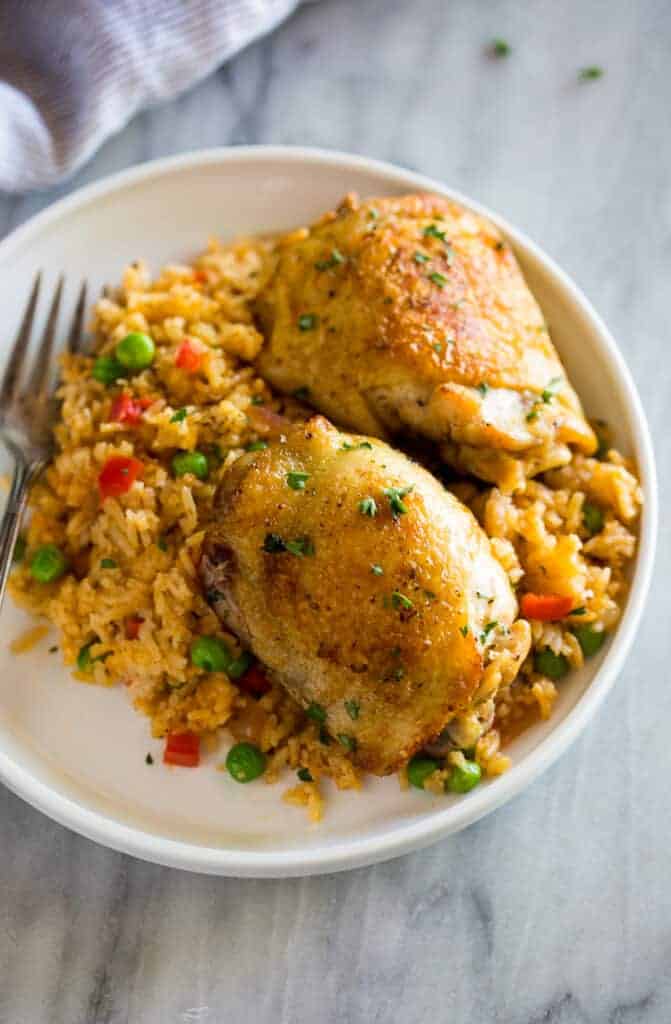 Spanish rice and chicken (arroz con pollo) served on a white plate with a fork.