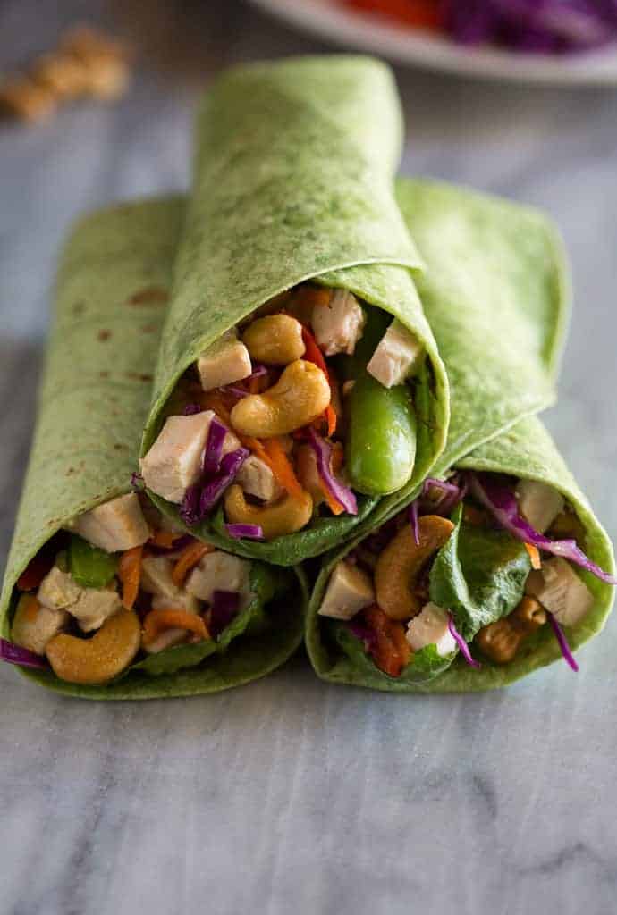 Three cashew chicken wraps stacked on one another with the filling (chicken cashews, and vegetables) facing the front.