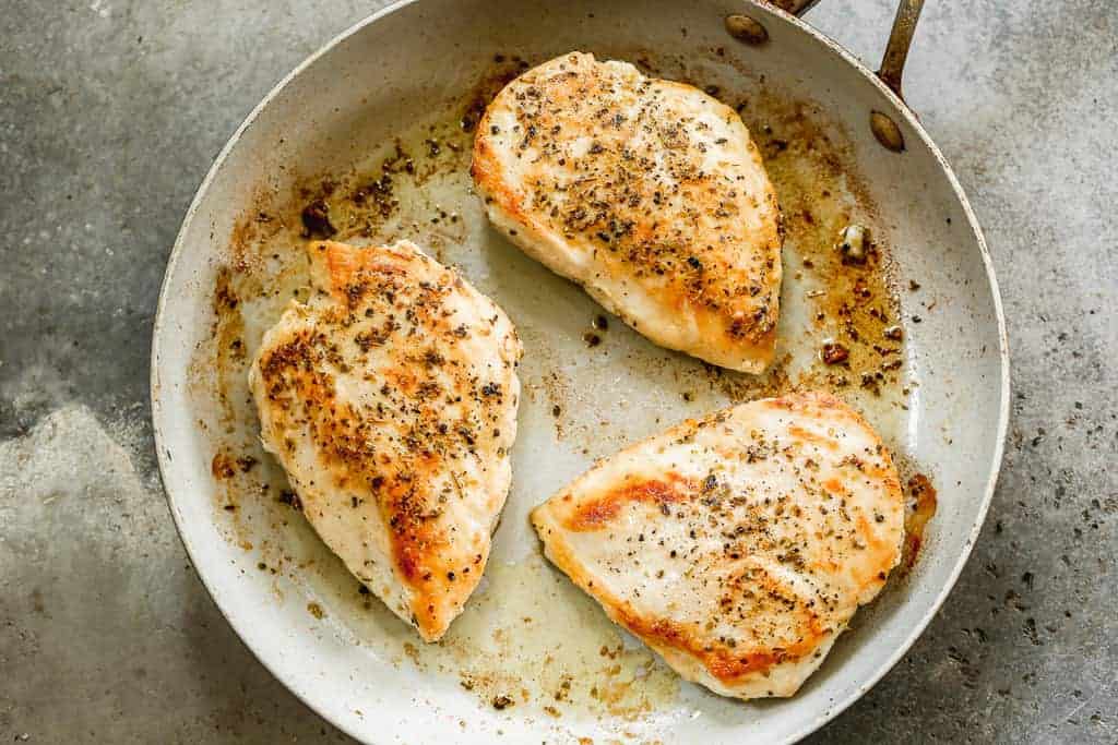 Three chicken breasts searing in 