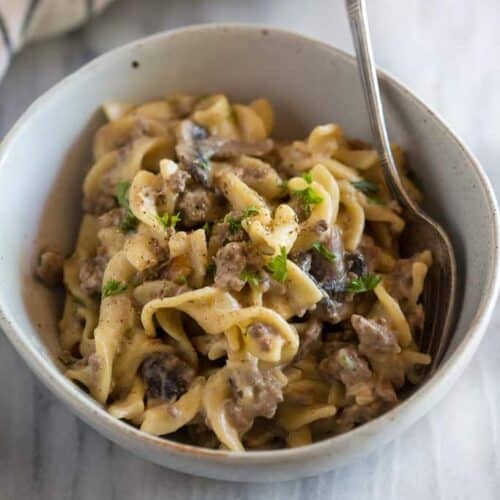 A bowl with hamburger stroganoff and a spoon.