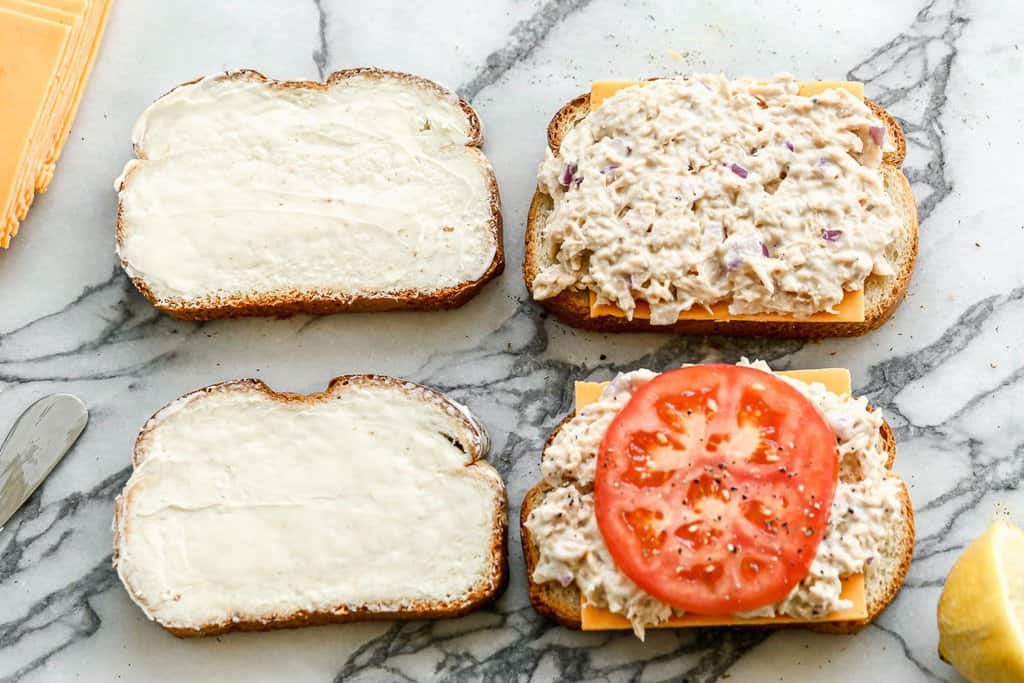 Four slices of bread layered with tuna, cheese and a slice of tomato.