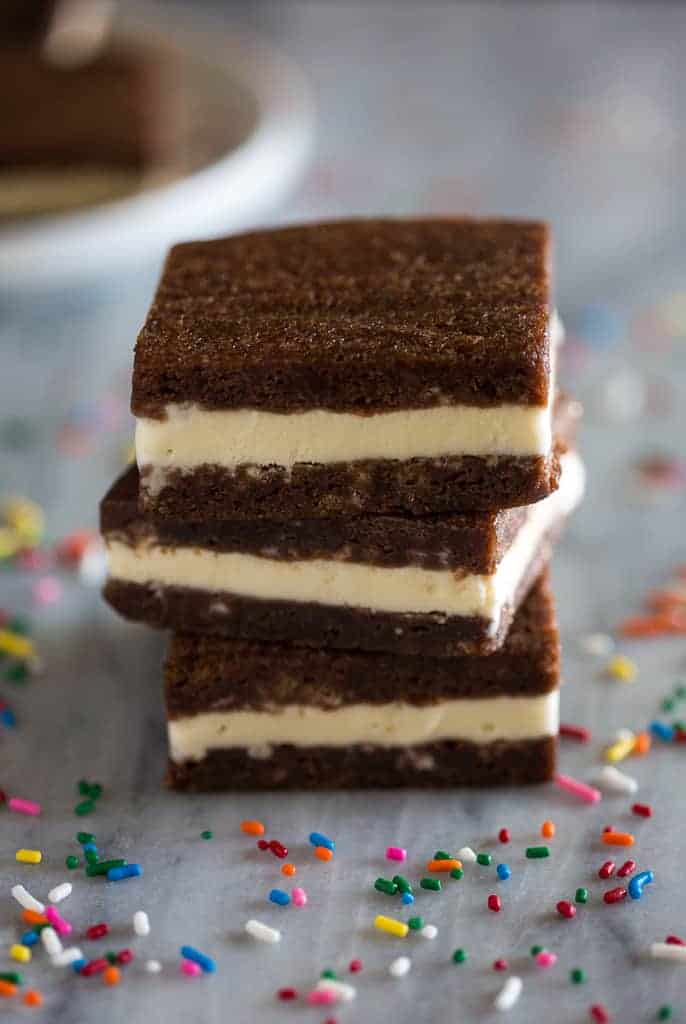 Three ice cream sandwich squares stacked on top of each other with colored sprinkles around them.