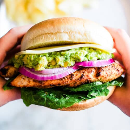 A homemade Grilled Chicken Sandwich being held, ready to take a bite.