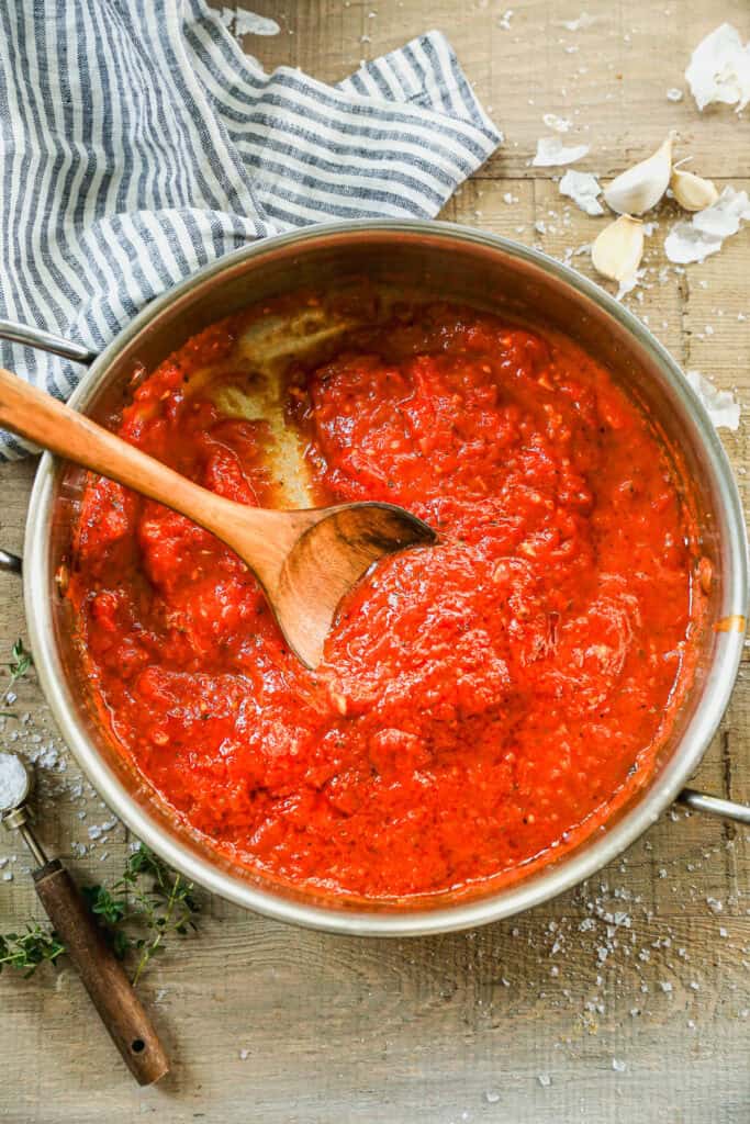 A classic Marinara Sauce recipe in a pan with a wooden spoon.