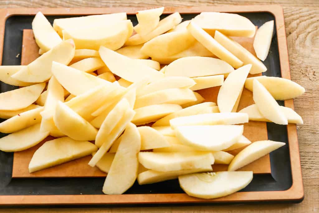 Sliced apples on a cutting board, prepared to make applesauce.