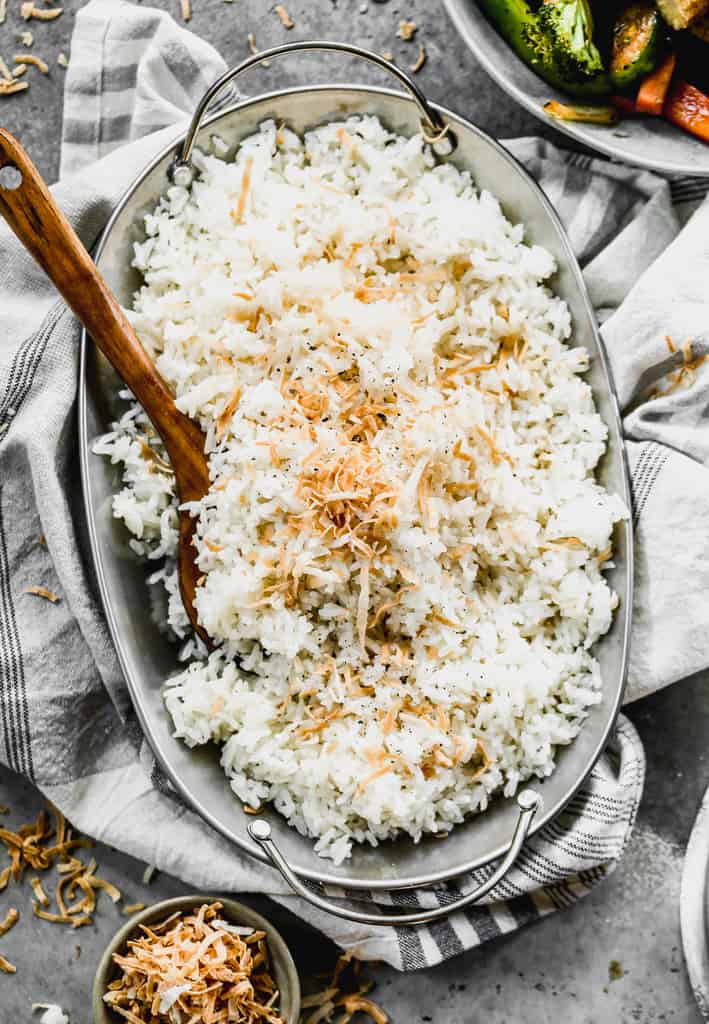 A platter full of homemade coconut rice, with a spoon in it for serving.