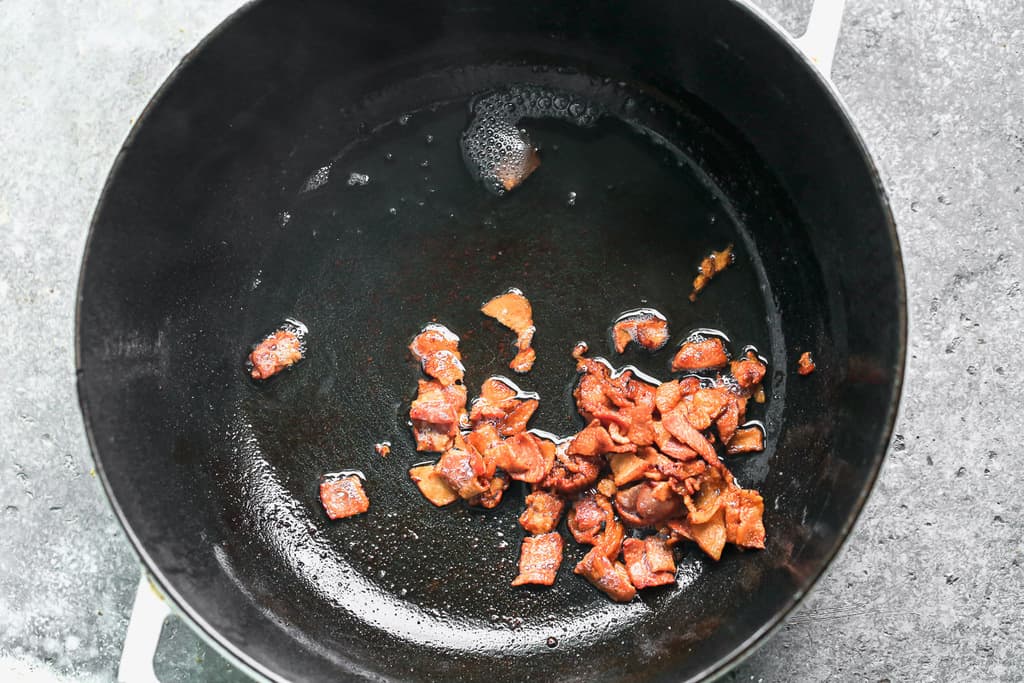 Chopped pieces of bacon cooking in a pot.