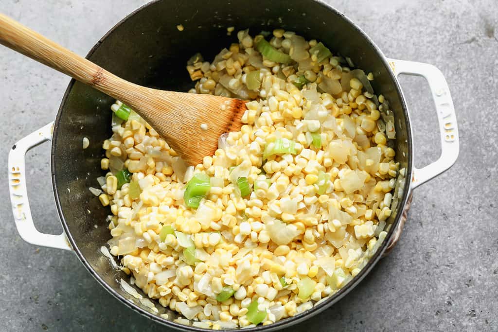 Fresh corn kernels added to a large pot with sautéed celery and onion, to make corn chowder.