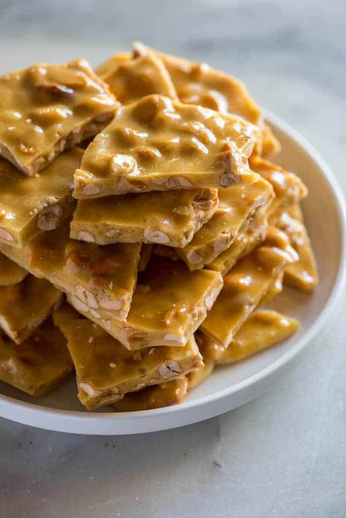 A plate with pieces of peanut brittle stacked on it.