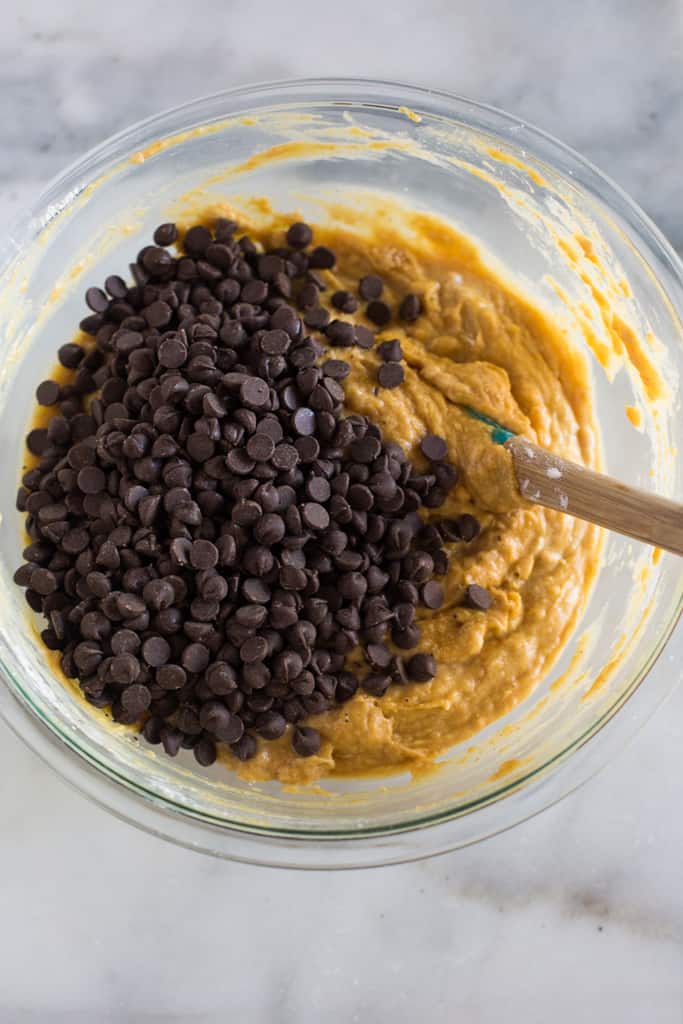 Chocolate chips added to a mixing bowl full of pumpkin bread batter.