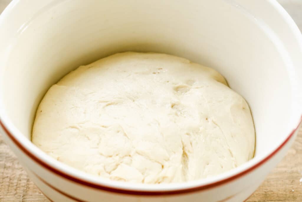 Risen roll dough in a mixing bowl.