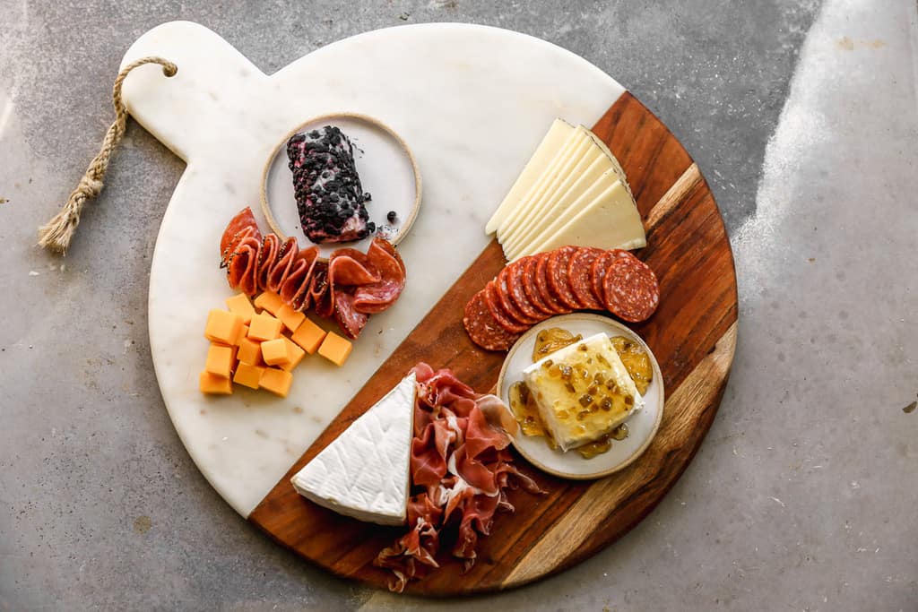 Cured meats arranged next to cheeses on a charcuterie board.