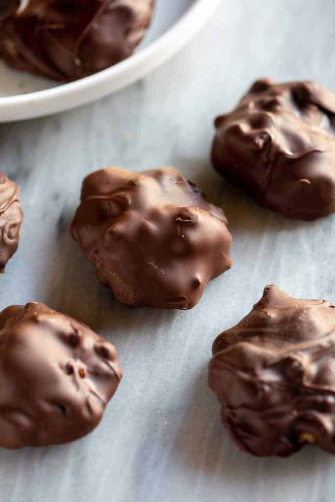 Homemade chocolate turtles candy on a marble board.