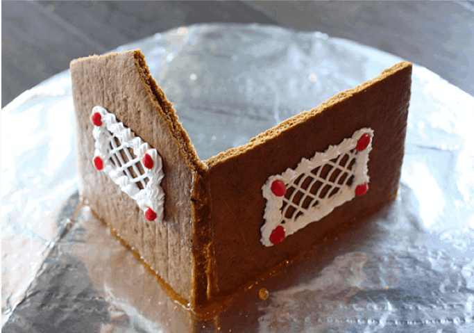 The back and side of a gingerbread house assembled on a board.